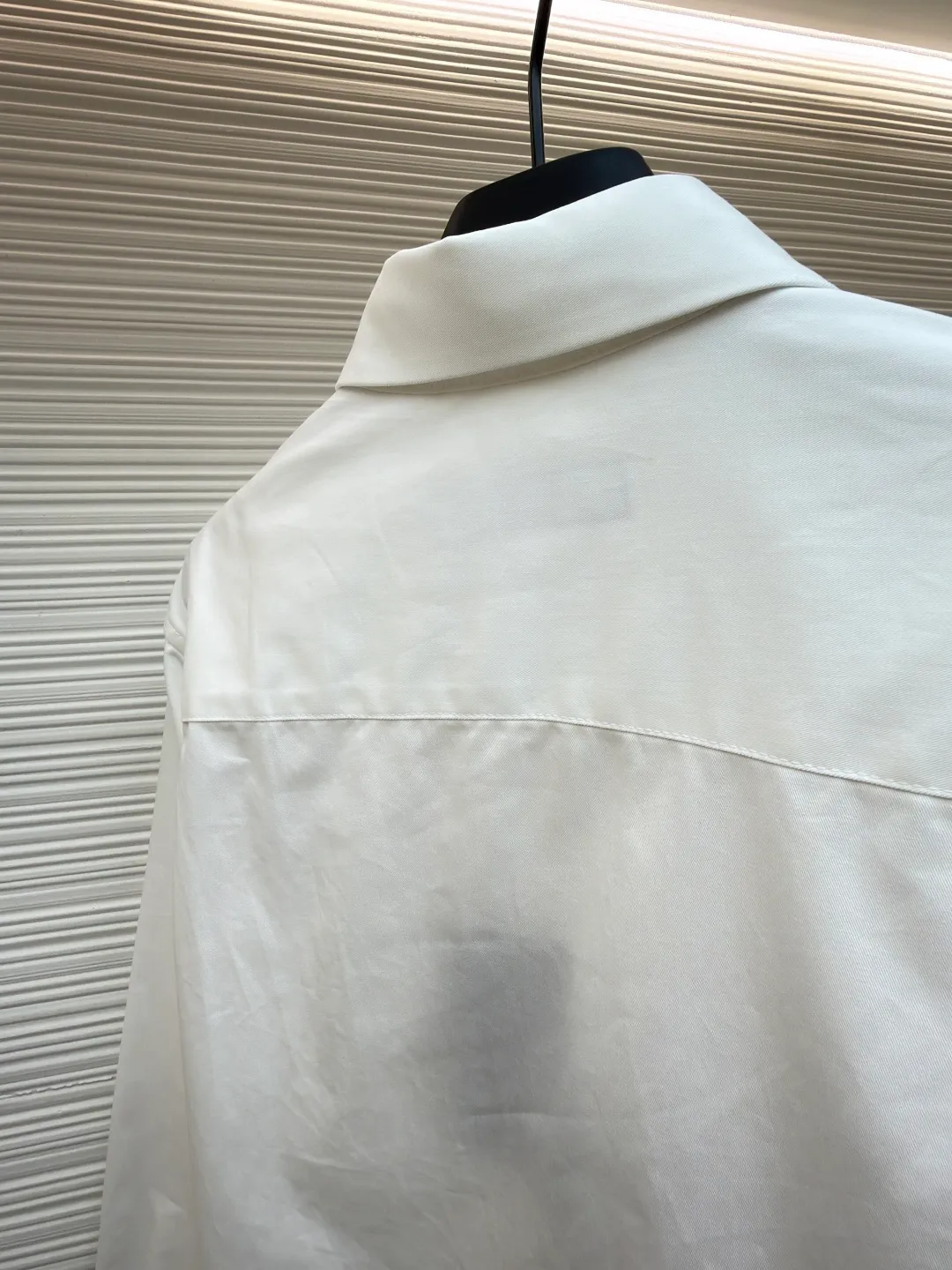 LOUIS VUITTON Embossed Pocket Lapel Shirt ●Original version: Purchased and developed for 3989 ●Item number: 1681491-B05 ●Fabric: Cotton twill woven fabric ●Technology: Concave embossed printing ●Color: white ●Version: Fitted version ●Weight: about 370 grams ●Size: XS-S-M-L ●Description: The twill pattern is obvious on the front of the fabric and blurry on the reverse. Single yarn is used in both warp and weft directions, and the linear density is close. The warp density of the fabric is slightly higher than the weft density, and the hand feel is relatively soft. The fabric has excellent stability, is not easy to deform, and prevents bulging; cotton fiber has good hygroscopicity, which keeps the fabric in a water balance, making people feel comfortable, and adding to the sophistication of the fabric. The concave and convex embossing process is formed by heating and shaping the upper and lower dies. The rollers press the fabric at a certain temperature, and the three-dimensional hierarchical convex surface is produced through mechanical embossing. The fabric produces a concave and convex pattern with a relief-style three-dimensional effect and a special gloss effect. The three-dimensional shape, pattern and text have a strong three-dimensional sense, adding a decorative art effect, clear layers, concentrated three-dimensional image, and accurate perspective angle. The collar can be adjusted with buttons for both formality and comfort; the pleats and tabs at the back are classic shirting techniques, with the pleats providing extra room for movement and the tabs keeping the shirt in shape when hanging. The button front uses custom-fit buttons that are positioned accordingly, and together these details ensure the shirt's functionality and crisp look. The overall wiring is straight and delicate, the fabric is comfortable and soft, and the color is consistent without color difference. It can be matched with the same style to create a fashionable look and control various occasions. Customized accessories, complete with three standards, same style for men and women!